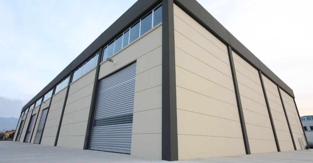 A low-angle view of a modern warehouse with roll-up doors.