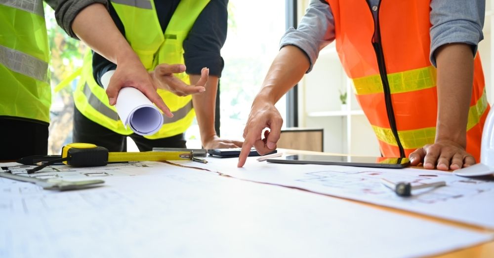 Construction workers review blueprints on a tabletop.