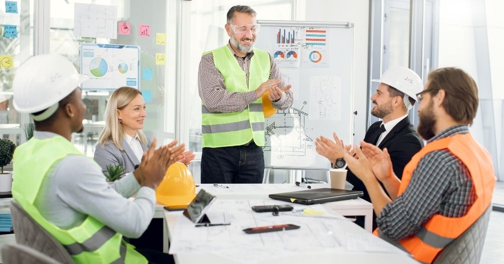 A team of engineers applauds during a meeting.