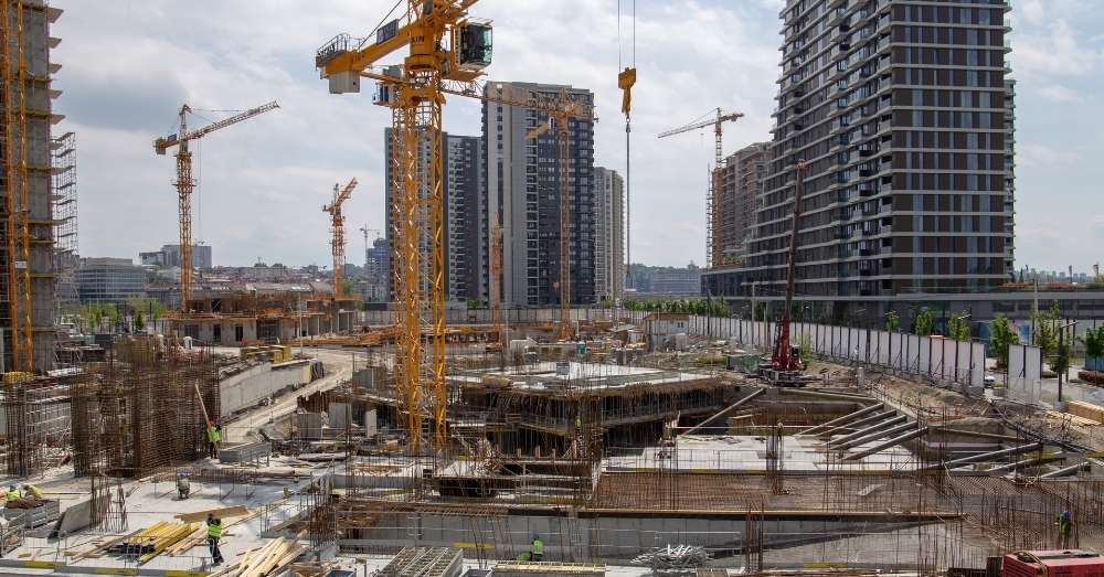 A massive urban construction site with tall cranes.