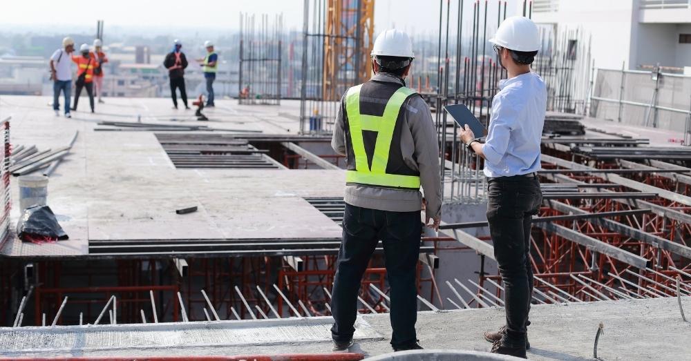 Two engineers review plans on a high-rise construction site.