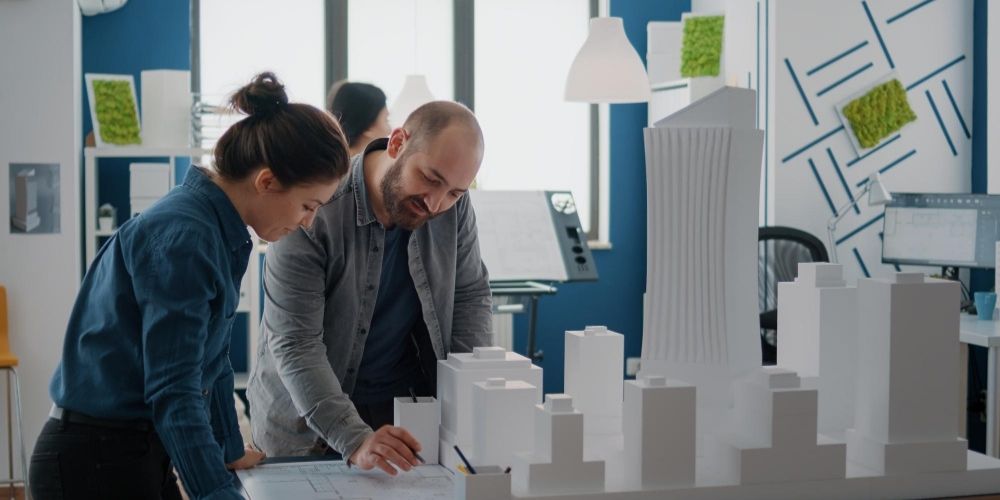 Builders guiding the client using a 3d miniature model of the building plan